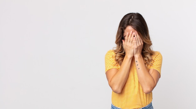 Mooie magere vrouw die zich verdrietig, gefrustreerd, nerveus en depressief voelt, haar gezicht met beide handen bedekt, huilt