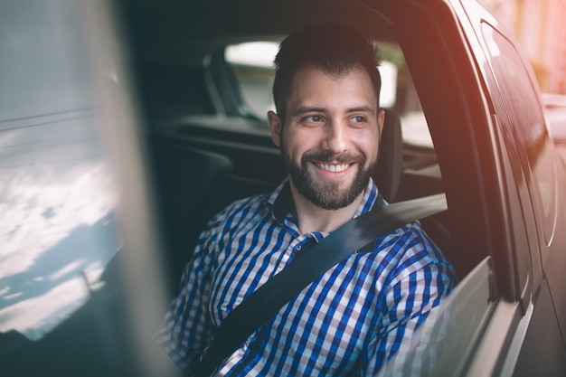 Mooie man die lacht zittend op de achterbank in de auto