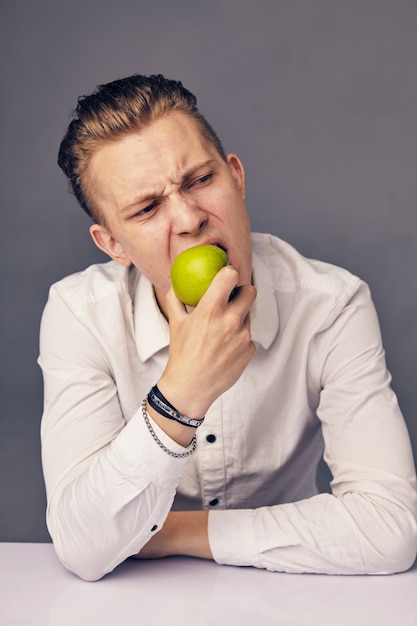 Mooie man eet appel, tegen donkere ondergrond