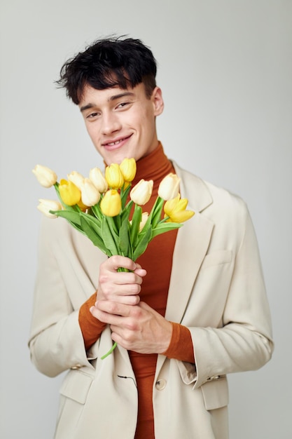 Mooie man in witte jas met een boeket gele bloemen elegante stijl modelstudio