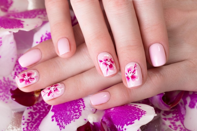 Mooie manicure geschoten met bloemen op vrouwelijke vingers Nagels ontwerp Close-up Foto genomen in de studio op een witte achtergrond