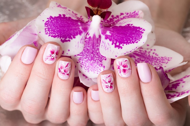 Mooie manicure geschoten met bloemen op vrouwelijke vingers Nagels ontwerp Close-up Foto genomen in de studio op een witte achtergrond