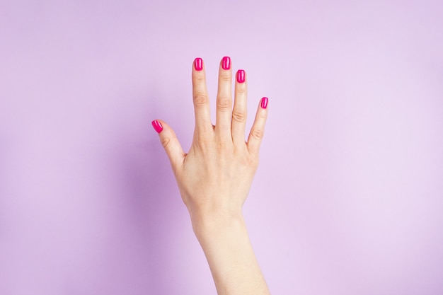 Mooie manicure. Mooie hand van een jonge vrouw op een paarse achtergrond.