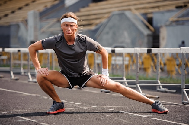 Mooie mannelijke atleet die zich uitstrekt vóór training,