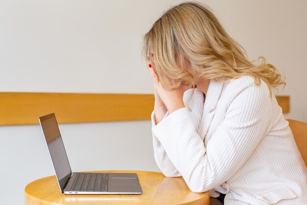 Mooie meid freelancer die zich moe en gestrest voelt terwijl ze een laptop gebruikt en op afstand werkt.