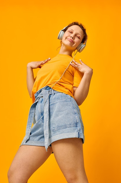 Mooie meid zomer stijl koptelefoon dans gele achtergrond ongewijzigd