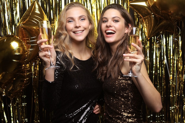 Mooie meisjes die Nieuwjaar vieren. Prachtige lachende jonge vrouwen genieten van feestviering, samen plezier hebben.