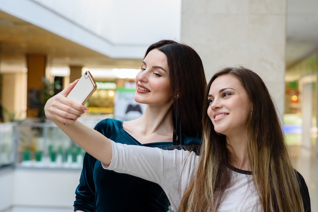 Mooie meisjes doen selfi in het winkelcentrum.