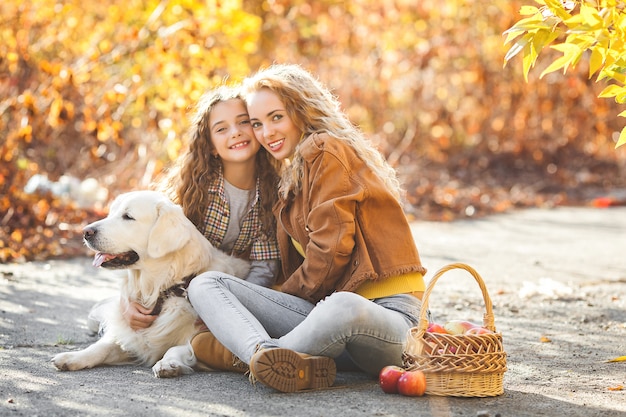 Mooie meisjes met golden retriever. Twee zussen buitenshuis plezier. Pet eigenaren in de herfst.