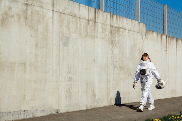 Mooie meisjesastronaut zonder helm op de achtergrond van een grijze muur. fantastisch ruimtepak.