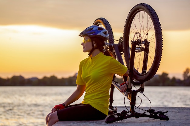 Foto mooie meisjesfietser met een fiets op de aard. gezonde levensstijl en sport. vrije tijd en hobby's