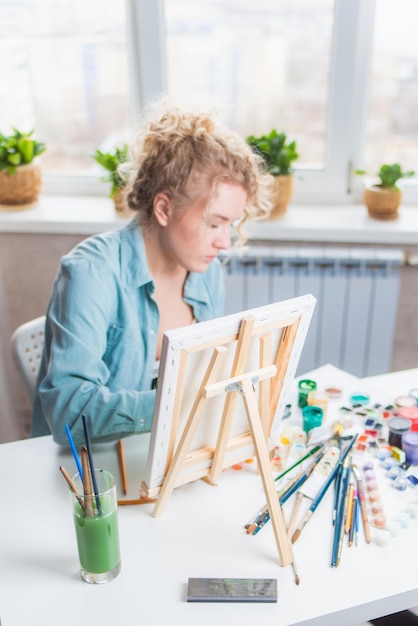 Mooie meisjeskunstenaar schildert thuis op canvas