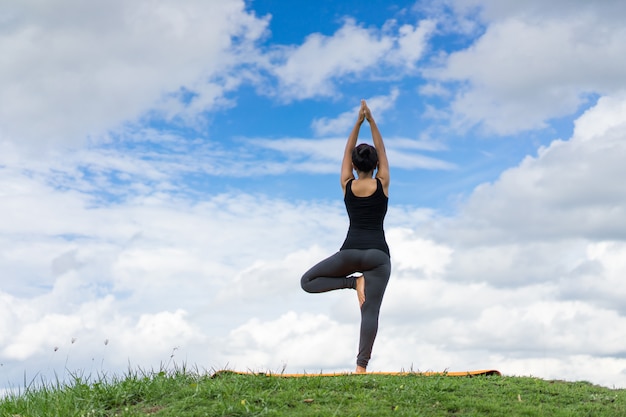 Mooie meisjesyoga in het park op zonnige dag mooie hemel.