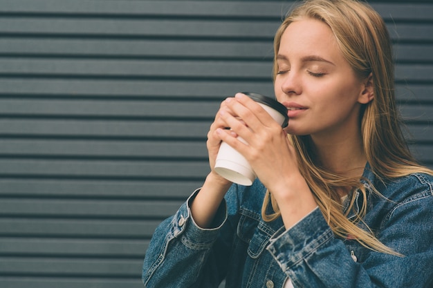 Mooie meisjeszitting in straat met ochtendkoffie en het ontspannen