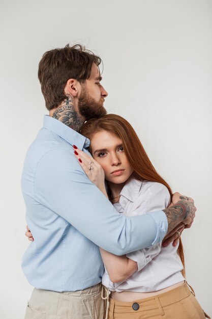 Mooie mode paar schoonheid roodharige vrouw en knappe man in casual stijlvolle elegante outfit knuffel op een witte achtergrond in de studio