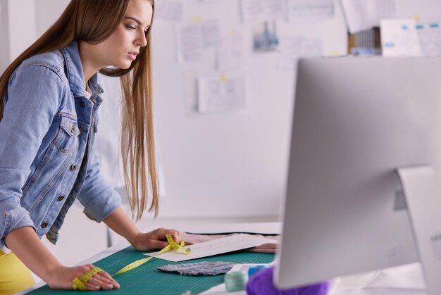 Mooie modeontwerper die zich dichtbij bureau in studio bevindt