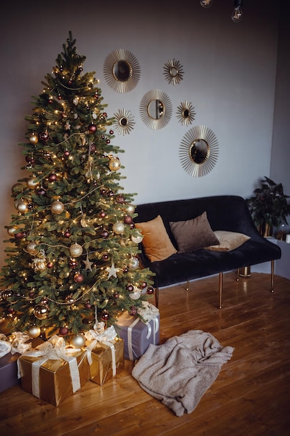 Mooie moderne grijze appartementkamer ingericht voor Nieuwjaar en Kerstmis Leuke kerstboom in een gele slinger en gouden kerstballen