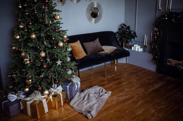 Mooie moderne grijze appartementkamer ingericht voor Nieuwjaar en Kerstmis Leuke kerstboom in een gele slinger en gouden kerstballen