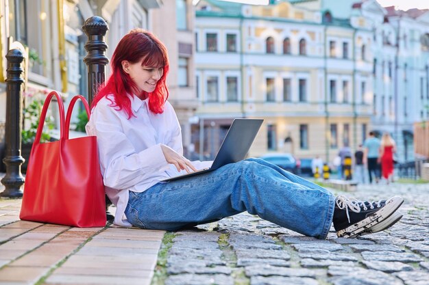 Foto mooie modieuze tiener student met laptop buiten