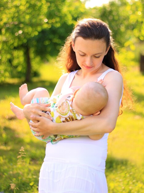 Mooie moeder en baby buitenshuis. Natuur. Schoonheidsmoeder en haar kind spelen samen in het park