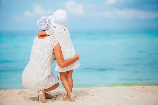 Mooie moeder en dochter op het strand genieten van zomervakantie