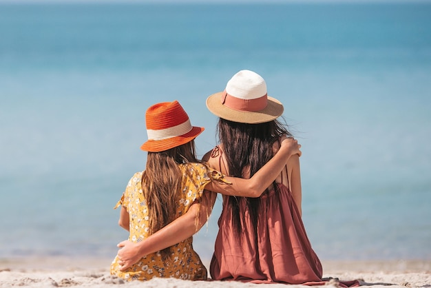 Mooie moeder en dochter op het strand genieten van zomervakantie