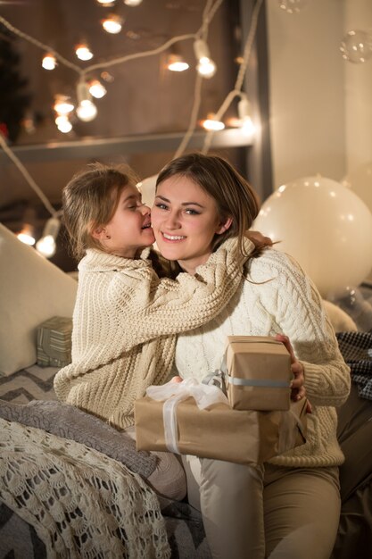 Mooie moeder en dochter openen een magisch kerstcadeau in het gezellige interieur van het huis. Nieuwjaar.