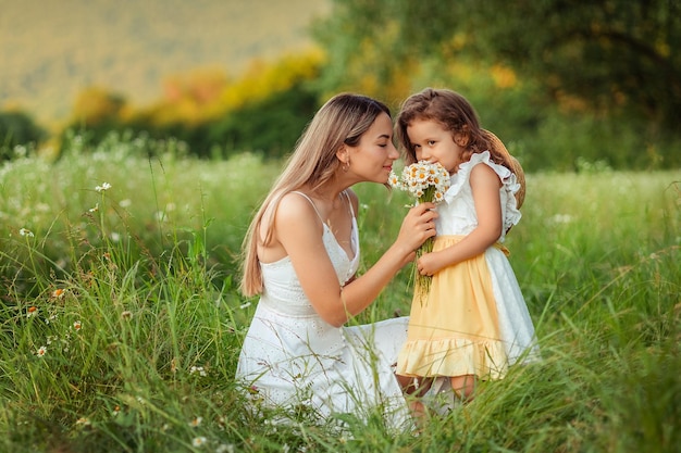Mooie moeder Haar dochtertje in witte jurken veel plezier tijdens een wandeling in de zomer