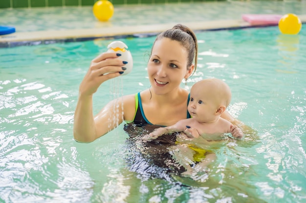 Mooie moeder leert schattig babymeisje zwemmen in een zwembad Kind heeft plezier in het water met moeder