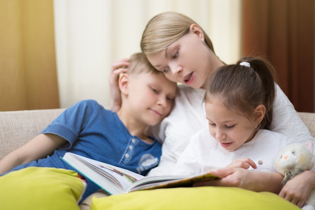 Mooie moeder leest een boek voor haar jonge kinderen