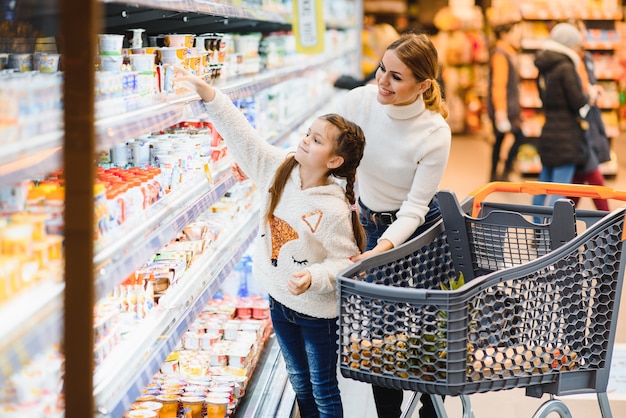 Mooie moeder met boodschappenmand met haar kind wandelen in de supermarkt