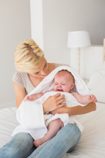 Mooie moeder met haar babymeisje dat in een handdoek wordt verpakt