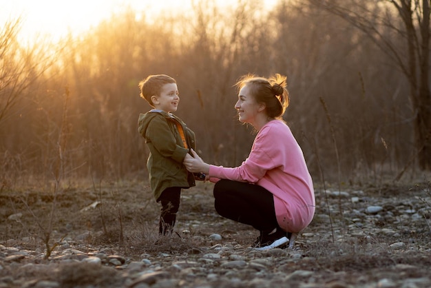 Mooie moeder speelt met haar zoon in de natuur tegen zonsondergang Moederdag concept