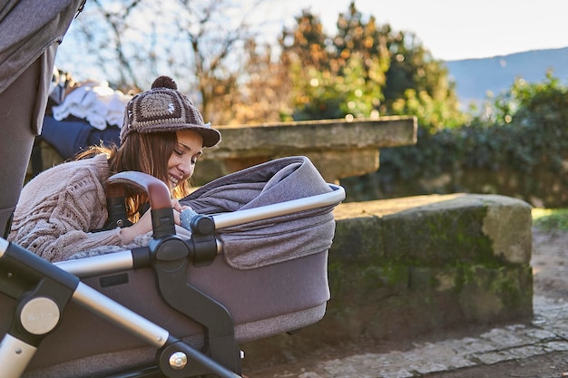 Foto mooie moeder vrouw met hoed die met haar baby speelt op een tweeling kinderwagen