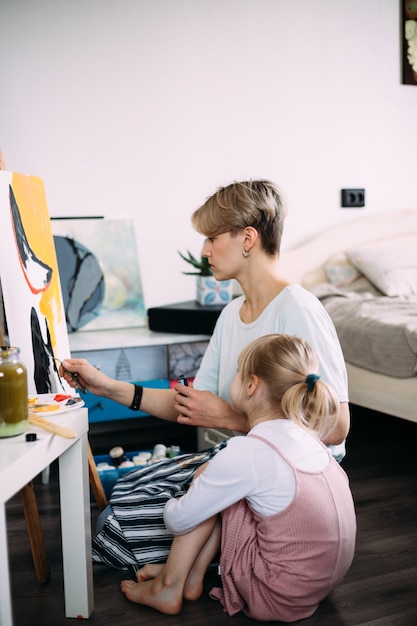 Mooie moederkunstenaar en haar kind schilderen thuis foto met acrylverf paint