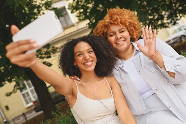 Mooie mooie gelukkige lesbische Afro-Amerikaanse paar knuffelen selfie maken rond stadsstraat