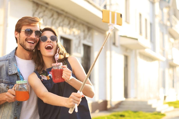 Mooie mooie jonge paar wandelen in de straten van de stad, knuffelen terwijl het nemen van een selfie.