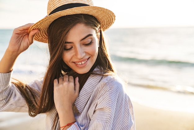 Mooie mooie jonge vrouw die zomerkleren draagt en tijd doorbrengt op het strand