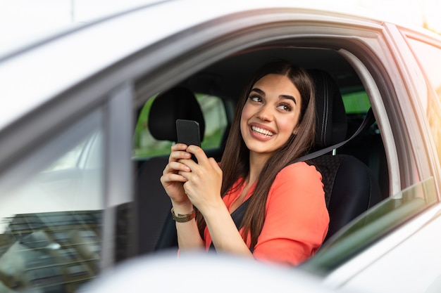 Mooie mooie jonge vrouw glimlach en gebruik mobiele telefoon het scherm in de auto aan te raken tijdens het reizen.