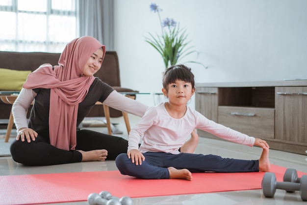 Mooie moslimmoeder en dochter trainen samen om gezond te worden. familievrouw en kind genieten van thuis oefenen