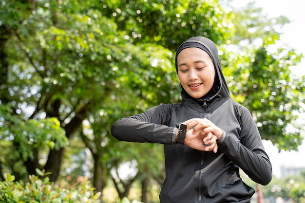 Mooie Moslimvrouw haar hartslag op slimme horloge tijdens het sporten buiten