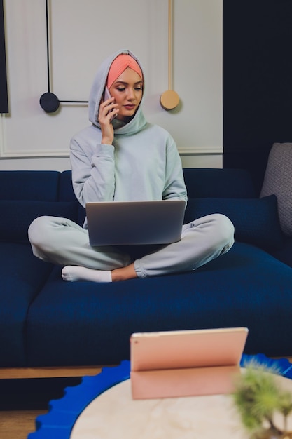 Mooie moslimvrouw van middelbare leeftijd met laptop thuis