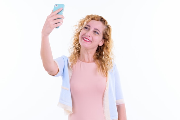 mooie multi-etnische vrouw met blond krullend haar geïsoleerd tegen een witte muur