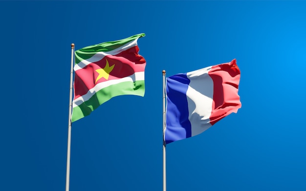 Mooie nationale vlaggen van Frankrijk en Suriname samen aan de hemel