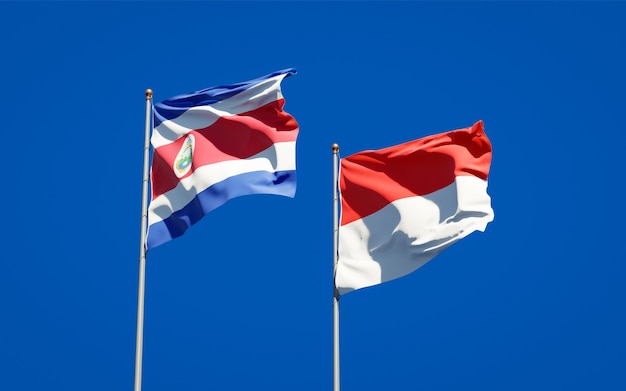 Mooie nationale vlaggen van Indonesië en Costa Rica samen op blauwe hemel