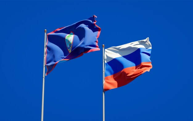 Mooie nationale vlaggen van Rusland en Guam samen op blauwe hemel. 3D-illustraties