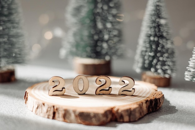 Mooie nieuwjaarswenskaart. Decoratieve nummers 2022 op houten standaard en groene sparren op grijze onscherpe achtergrond. Gelukkig nieuwjaar 2022.