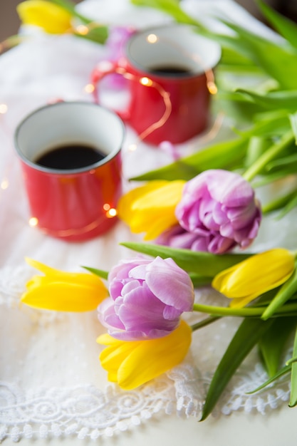 Mooie ochtend, twee kopjes koffie en een boeket heldere en mooie tulpen. Detailopname.