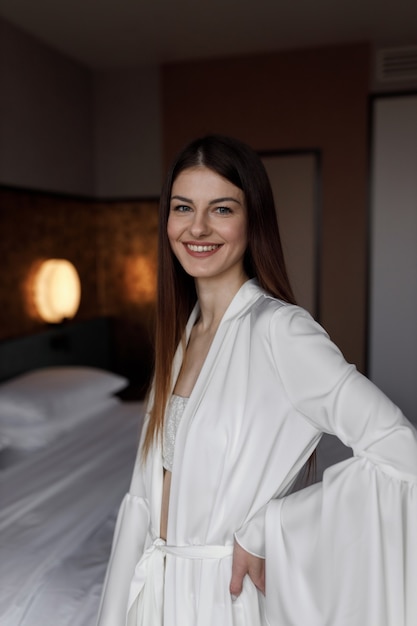 Mooie ochtend van de bruid in een lichte boudoirjurk in een hotel op het bed. Een jong meisje poseert en lacht voor de bruiloft.