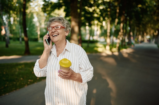 Mooie oma met behulp van mobiele telefoon in zomerpark